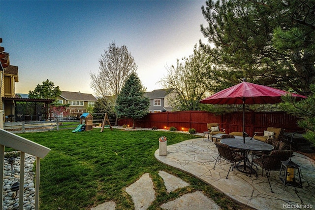 yard at dusk featuring a patio and a playground
