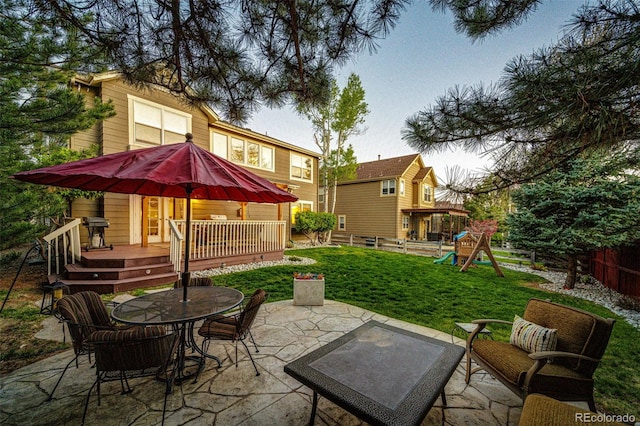 view of patio / terrace featuring a deck, outdoor dining area, a playground, and a grill