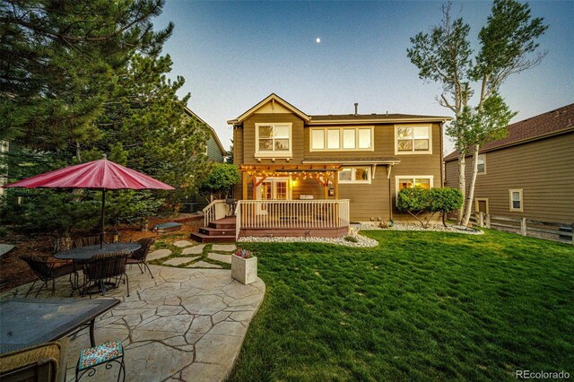 rear view of house with a deck, a patio area, and a lawn
