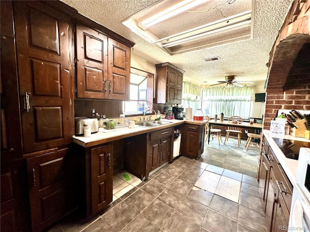 kitchen featuring a textured ceiling, ceiling fan, light countertops, and dark brown cabinetry