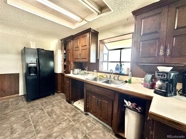kitchen with black fridge with ice dispenser, a textured ceiling, light countertops, and dark brown cabinetry