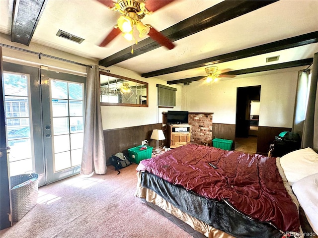 bedroom featuring wainscoting, carpet, wooden walls, beamed ceiling, and access to exterior