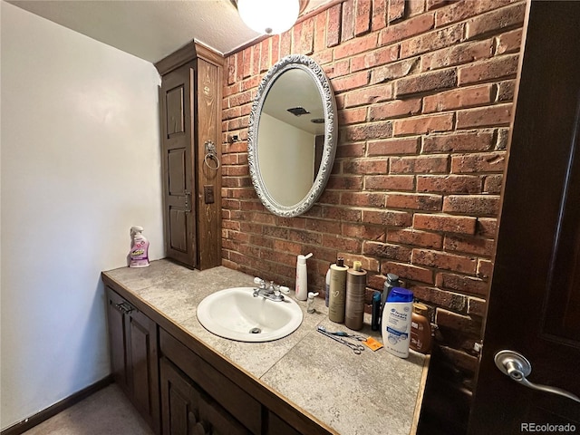 bathroom with vanity and brick wall