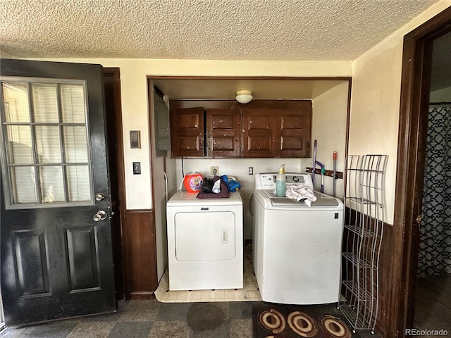 washroom featuring cabinet space, washing machine and dryer, and a textured ceiling