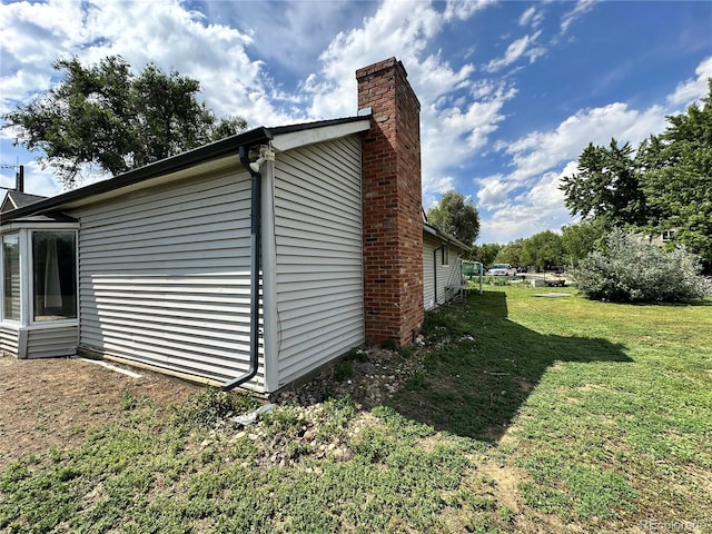 view of property exterior with a chimney and a lawn