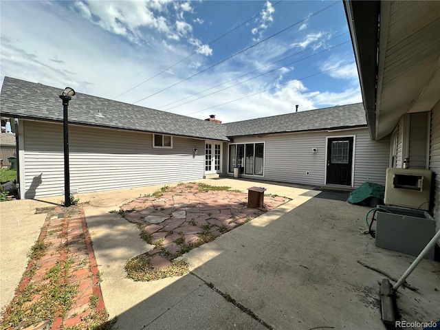 back of property with a patio area and a shingled roof