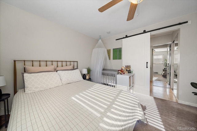 bedroom with carpet, ceiling fan, and a barn door