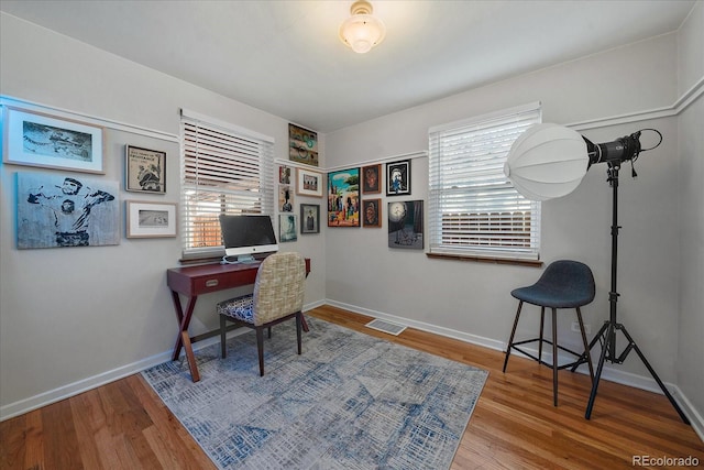 office with a healthy amount of sunlight and hardwood / wood-style flooring