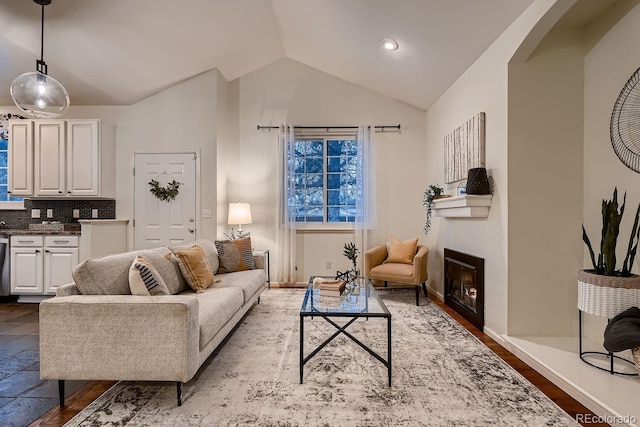 living area with lofted ceiling, a glass covered fireplace, arched walkways, and baseboards