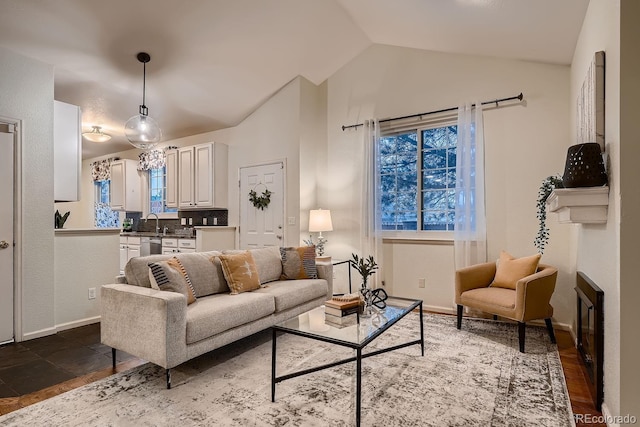 living room with lofted ceiling, a glass covered fireplace, and baseboards