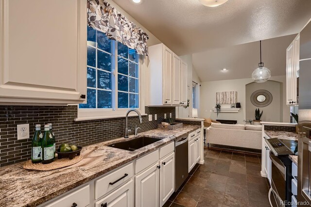 kitchen featuring light stone counters, pendant lighting, tasteful backsplash, white cabinetry, and a sink