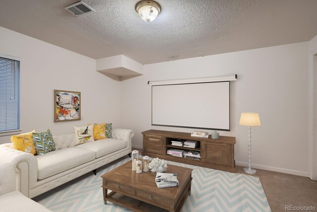 cinema featuring baseboards, visible vents, a textured ceiling, and light colored carpet