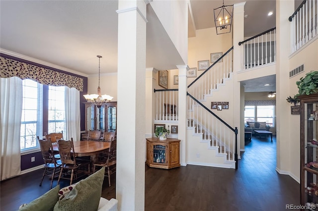 dining area featuring decorative columns, visible vents, stairway, ornamental molding, and wood finished floors