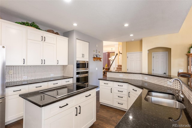 kitchen with stainless steel appliances, a sink, white cabinetry, backsplash, and dark wood-style floors