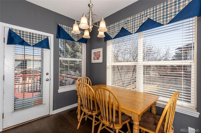dining room with an inviting chandelier, plenty of natural light, baseboards, and wood finished floors