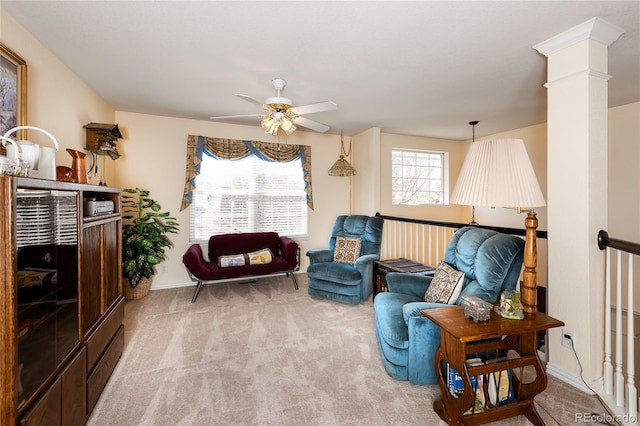 living area featuring carpet floors, ornate columns, and ceiling fan