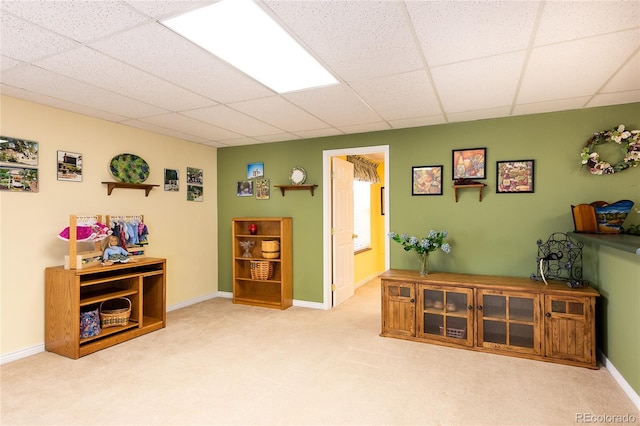 sitting room with carpet, a paneled ceiling, and baseboards