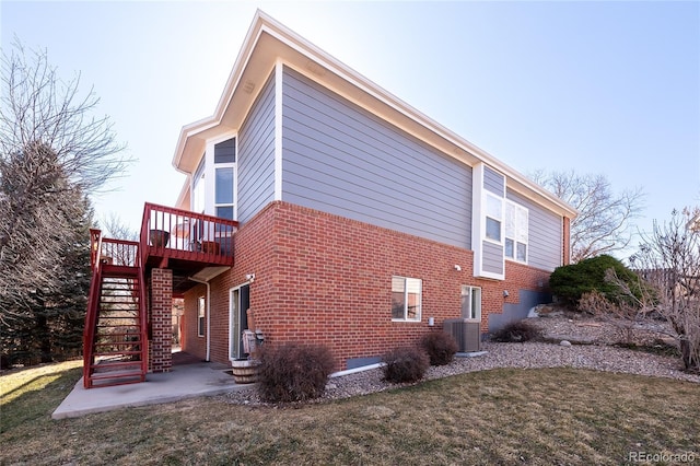 view of property exterior with brick siding, central air condition unit, a lawn, stairway, and a deck