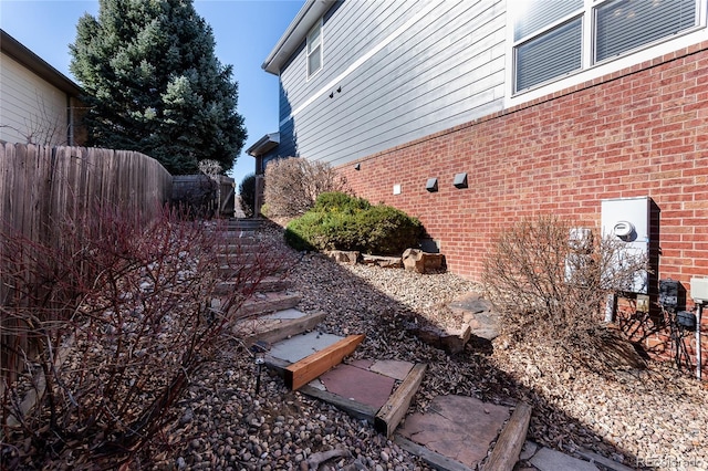 view of property exterior with brick siding and fence