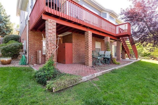 back of house featuring a yard, brick siding, stairway, and a patio area