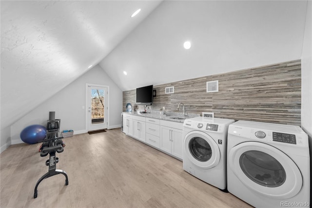 laundry area featuring sink, light hardwood / wood-style flooring, washing machine and dryer, and cabinets