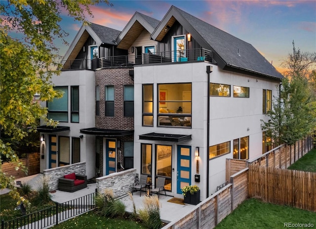 back of house featuring a fenced backyard, roof with shingles, and a balcony