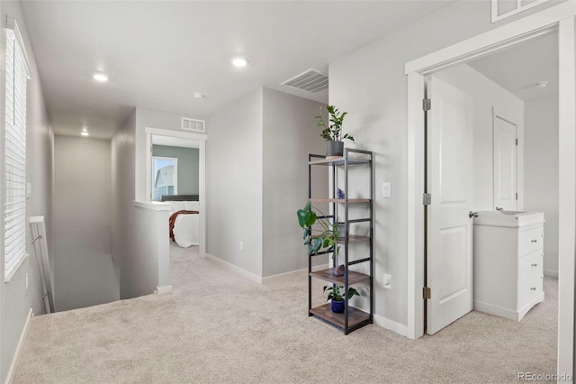 hallway featuring light colored carpet