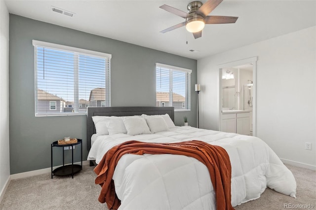 bedroom with ceiling fan, light colored carpet, and ensuite bathroom