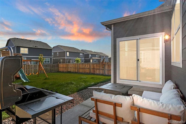 patio terrace at dusk with an outdoor living space, a playground, and a yard