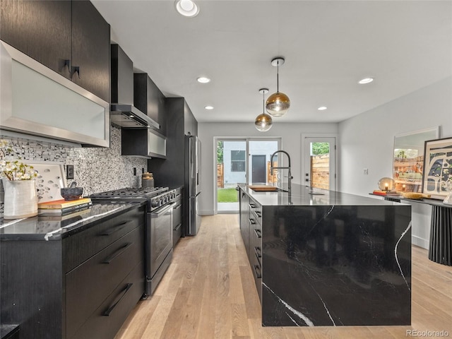 3715 Kalamath St, Denver, CO 80211 - kitchen featuring stainless steel appliances, a sink, wall chimney exhaust hood, dark cabinets, and tasteful backsplash