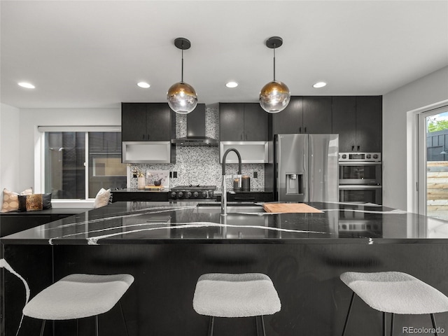 3715 Kalamath St, Denver, CO 80211 - kitchen with wall chimney range hood, stainless steel appliances, dark cabinetry, dark countertops, and hanging light fixtures