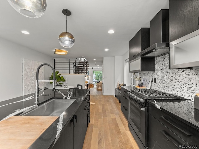 3715 Kalamath St, Denver, CO 80211 - kitchen with a sink, gas range, dark cabinetry, wall chimney range hood, and light wood finished floors