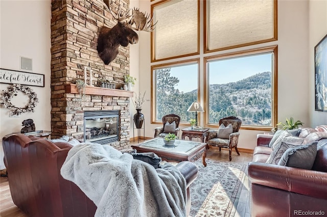 9659 S Turkey Creek Rd, Morrison, CO 80465 - living area featuring wood finished floors, a fireplace, baseboards, a towering ceiling, and a mountain view