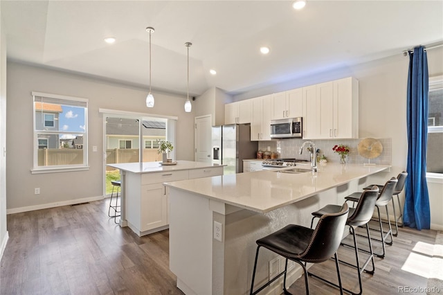 254 Gila Trl, Ault, CO 80610 - kitchen featuring stainless steel appliances, a breakfast bar, light wood-style floors, tasteful backsplash, and white cabinets