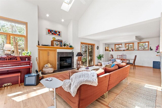 597 Pine Glade Rd, Nederland, CO 80466 - living area with plenty of natural light, a tiled fireplace, wood finished floors, high vaulted ceiling, and recessed lighting