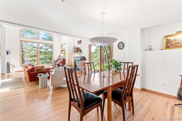 597 Pine Glade Rd, Nederland, CO 80466 - dining space featuring plenty of natural light, light wood finished floors, a glass covered fireplace, and baseboards