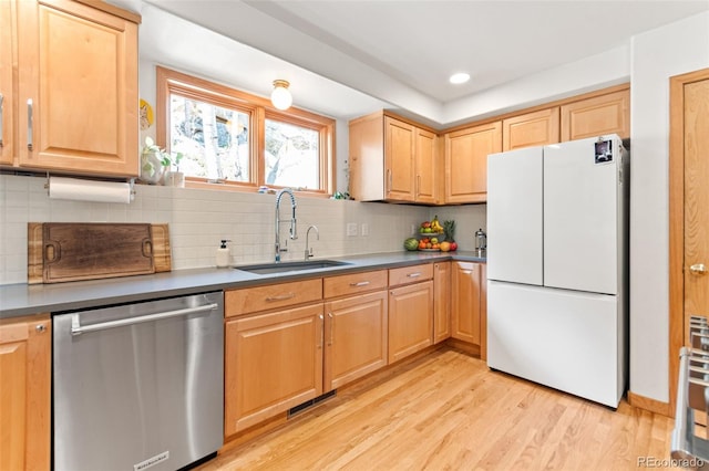 597 Pine Glade Rd, Nederland, CO 80466 - kitchen with freestanding refrigerator, stainless steel dishwasher, a sink, light wood-style flooring, and decorative backsplash