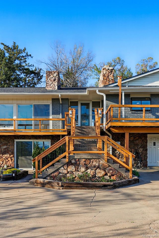 8090 Newton St, Westminster, CO 80031 - view of front of home with stone siding, a chimney, stairs, and a deck