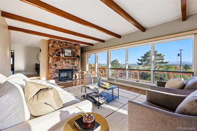 8090 Newton St, Westminster, CO 80031 - living area featuring beamed ceiling, a stone fireplace, wood finished floors, and baseboards