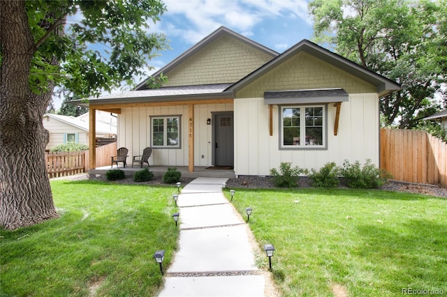 view of front of home with a porch, board and batten siding, a front yard, and fence