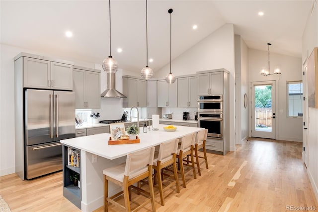 4711 S Logan St, Englewood, CO 80113 - kitchen featuring appliances with stainless steel finishes, wall chimney range hood, gray cabinets, light countertops, and light wood-type flooring