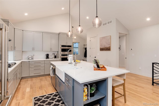 4711 S Logan St, Englewood, CO 80113 - kitchen featuring gray cabinetry, lofted ceiling, a sink, a kitchen breakfast bar, and light wood finished floors