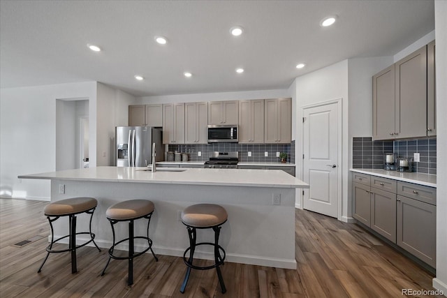 18001 Herrera Dr, Parker, CO 80134 - kitchen featuring appliances with stainless steel finishes, gray cabinetry, a sink, a kitchen island with sink, and dark wood finished floors