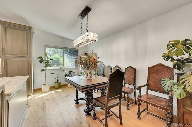 dining area with an inviting chandelier, vaulted ceiling, and light hardwood / wood-style floors