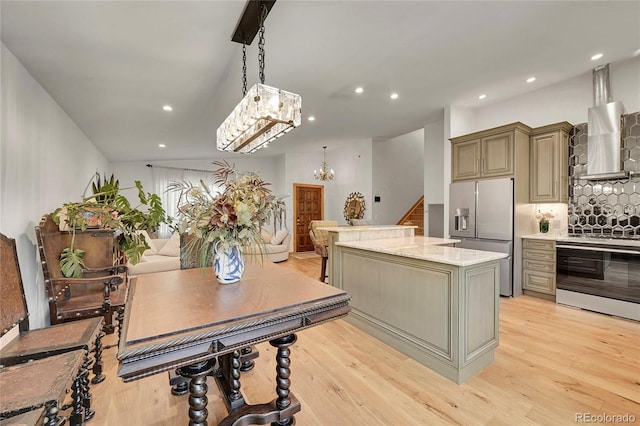 kitchen featuring pendant lighting, stainless steel appliances, a center island, light hardwood / wood-style flooring, and wall chimney range hood