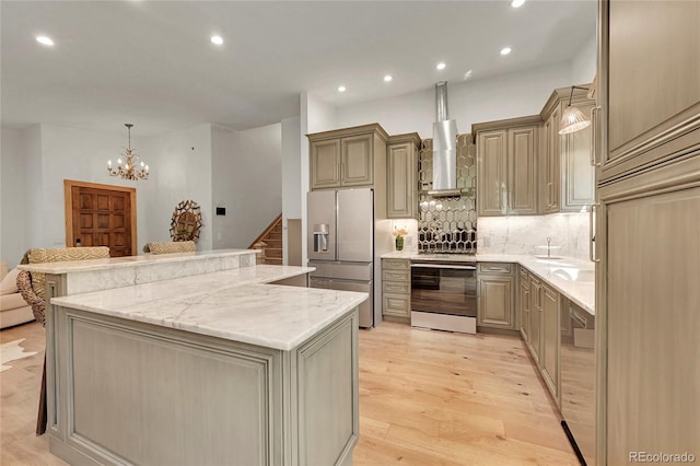 kitchen featuring a center island, hanging light fixtures, light hardwood / wood-style flooring, appliances with stainless steel finishes, and light stone countertops