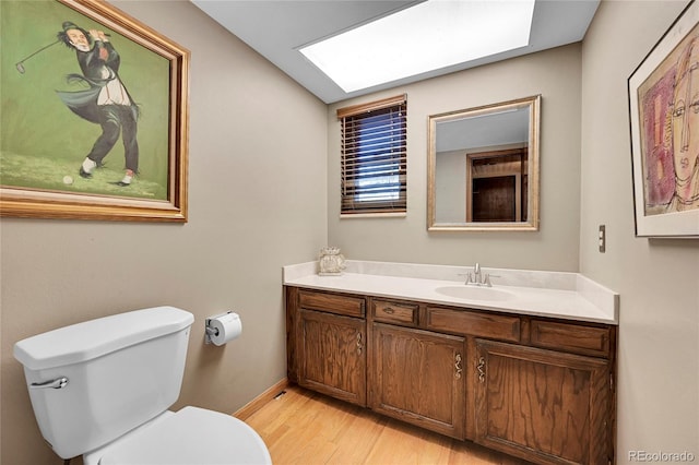 bathroom with hardwood / wood-style floors, vanity, toilet, and vaulted ceiling