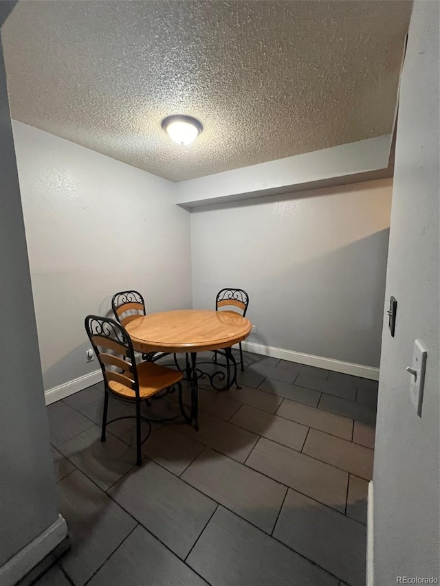 dining space with a textured ceiling, baseboards, and tile patterned flooring