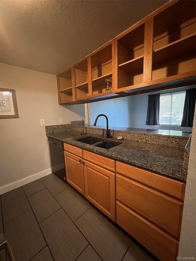 kitchen featuring a sink, black dishwasher, open shelves, dark stone counters, and baseboards