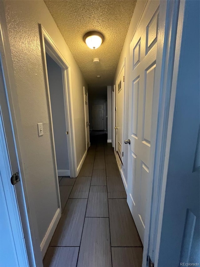 corridor featuring a textured ceiling and baseboards